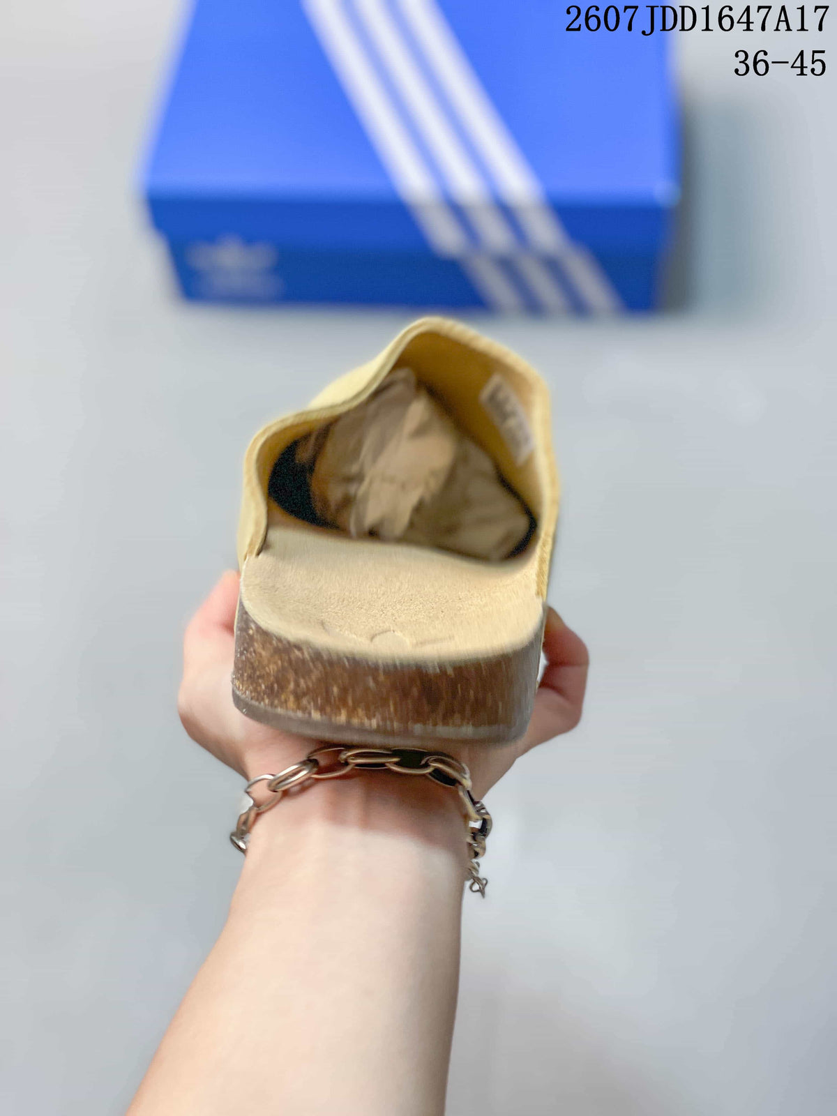 Rear view of the beige slip-on mule showing the open heel, rounded sole profile, and textured upper.