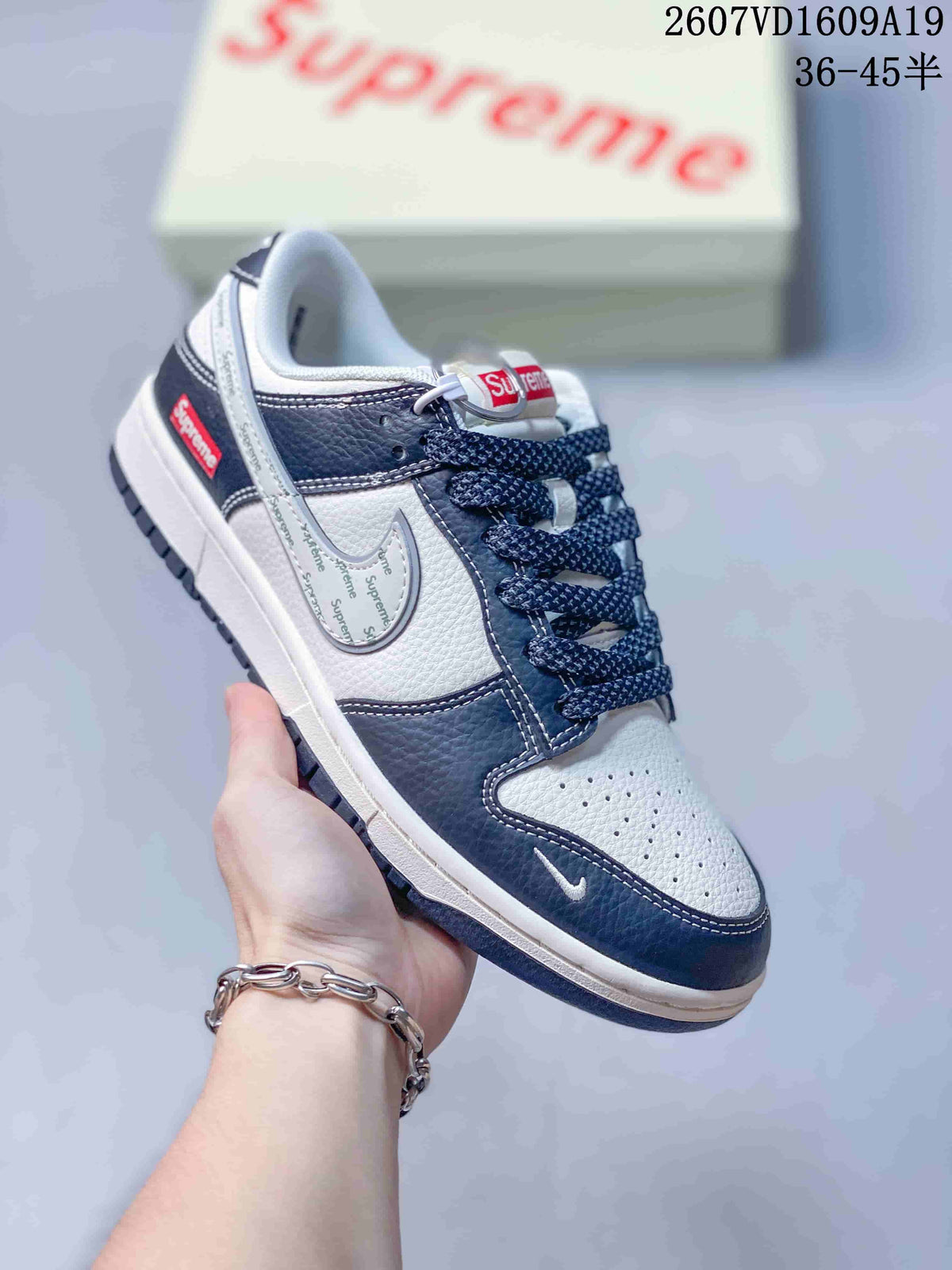 Close-up of a white and navy Nike Dunk Low sneaker with perforated toe box, navy overlays and decorative side branding.