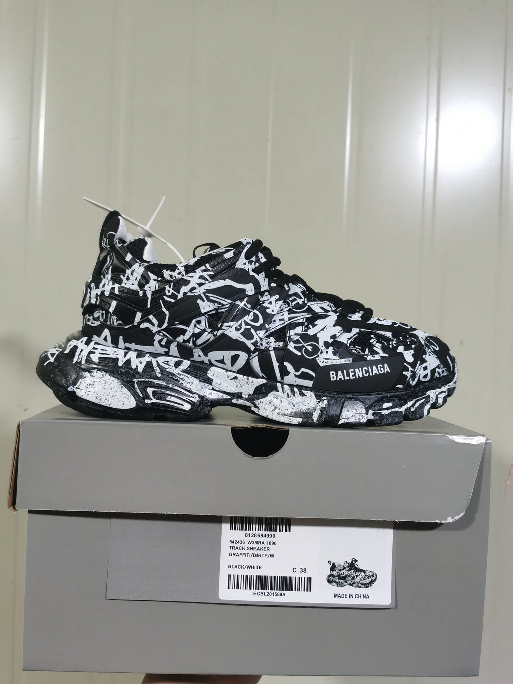Side profile of the black-and-white Balenciaga Track sneaker displayed on its box; the label shows style code 542436 W3RRA 1090, colorway GRAFFITI/DIRTY/WHITE, and size C 38.