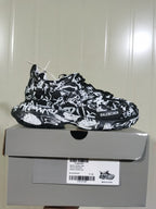 Side profile of the black-and-white Balenciaga Track sneaker displayed on its box; the label shows style code 542436 W3RRA 1090, colorway GRAFFITI/DIRTY/WHITE, and size C 38.
