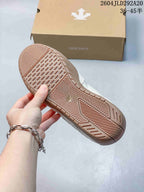 Close-up of the patterned gum-colored outsole on a cream Descente sneaker.