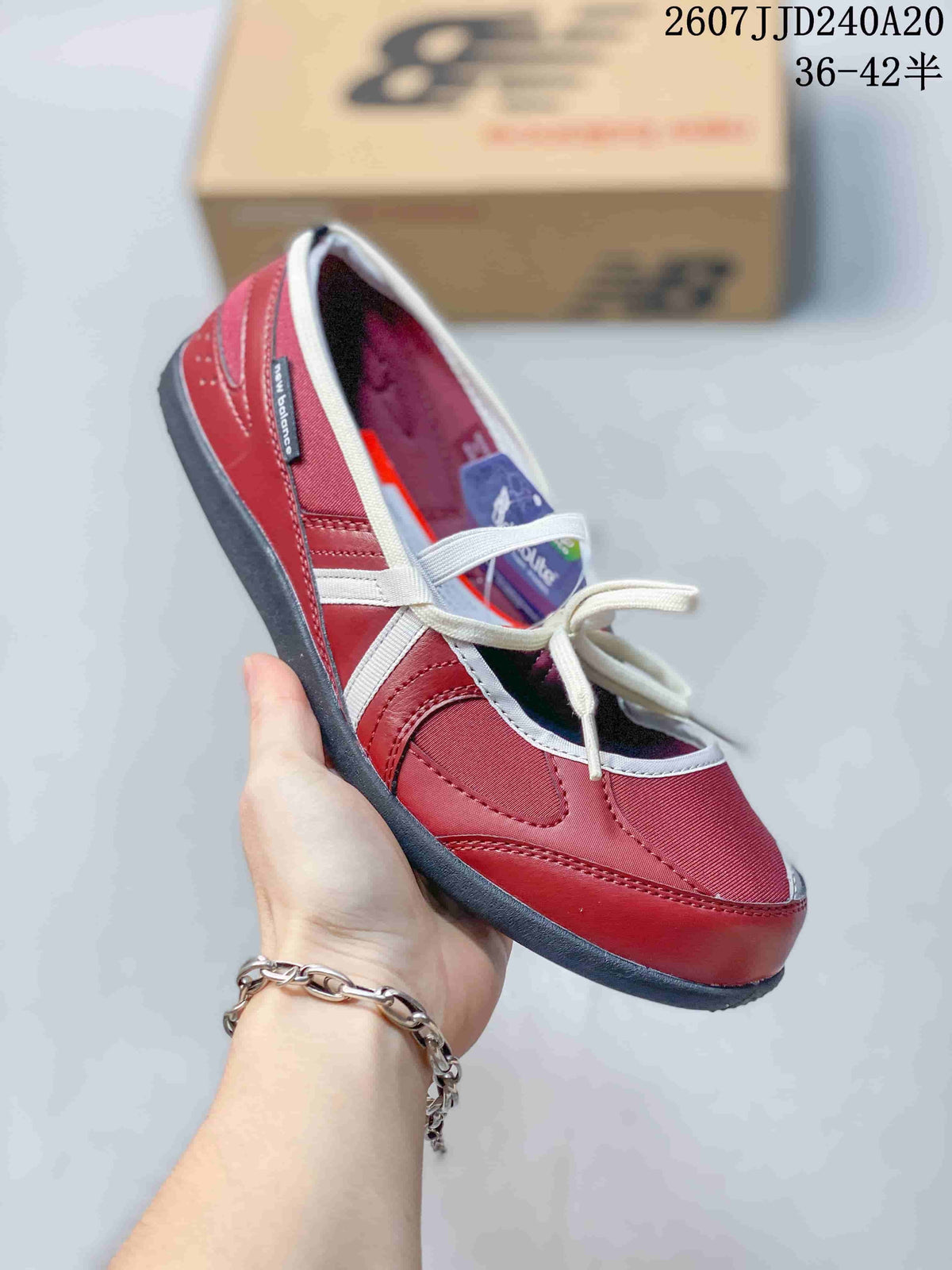 Side view of the red New Balance shoe showing the layered panels, white laces, and dark outsole.