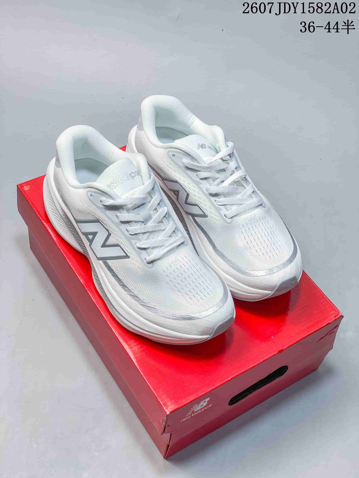 Pair of white and silver New Balance running shoes on a red shoe box.