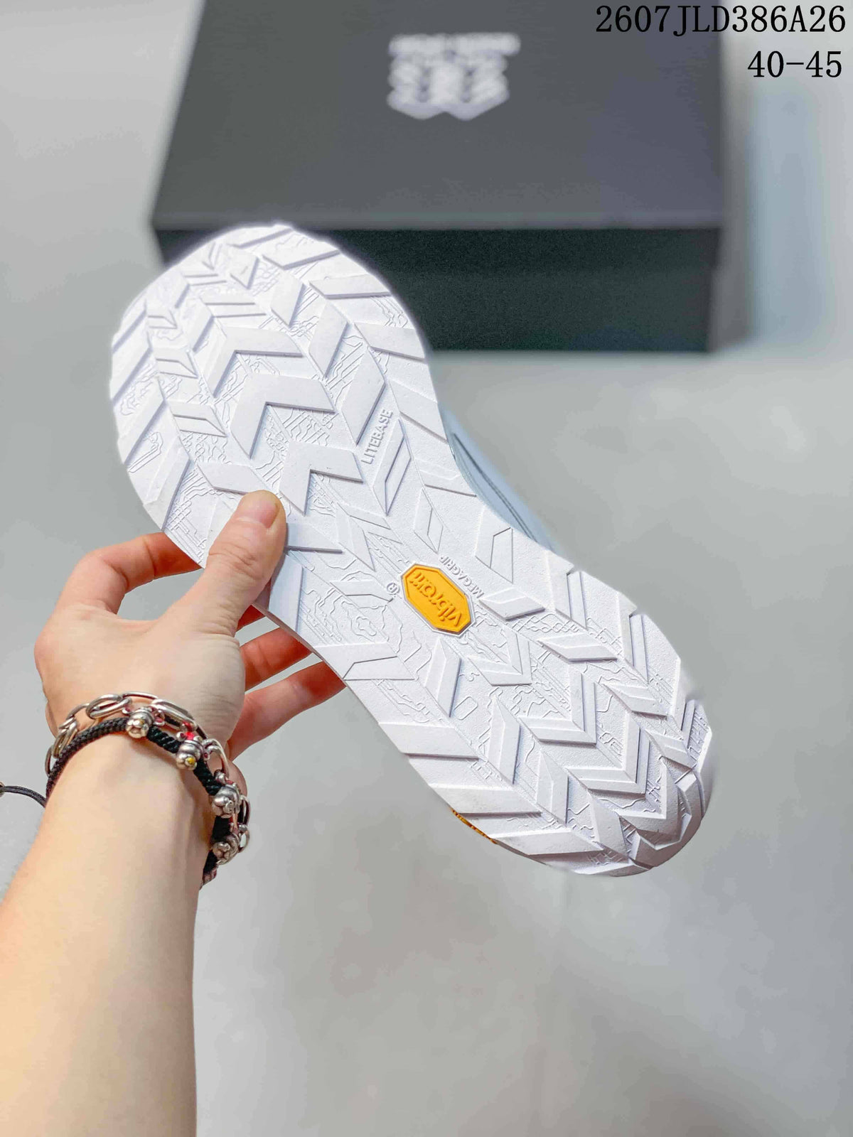 Underside view of the white sneaker showing a geometric tread pattern and a yellow outsole insert.