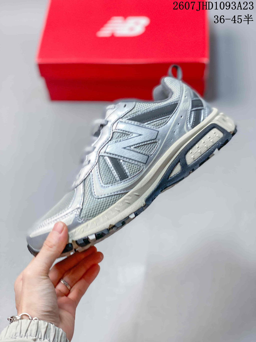 Side profile of the grey low-top sneaker showing mesh panels, layered overlays, lace area, and textured outsole.