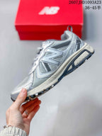 Side profile of the grey low-top sneaker showing mesh panels, layered overlays, lace area, and textured outsole.