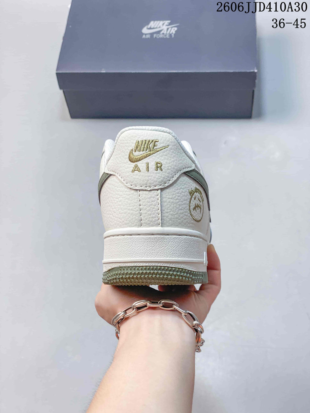 Rear view of the white sneaker with gold-toned heel branding and green outsole