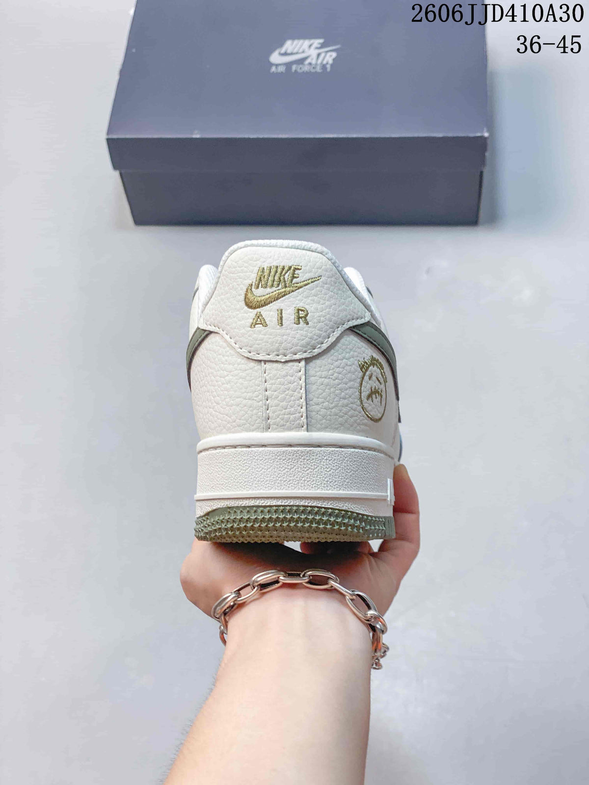 Rear view of the white sneaker with gold-toned heel branding and green outsole