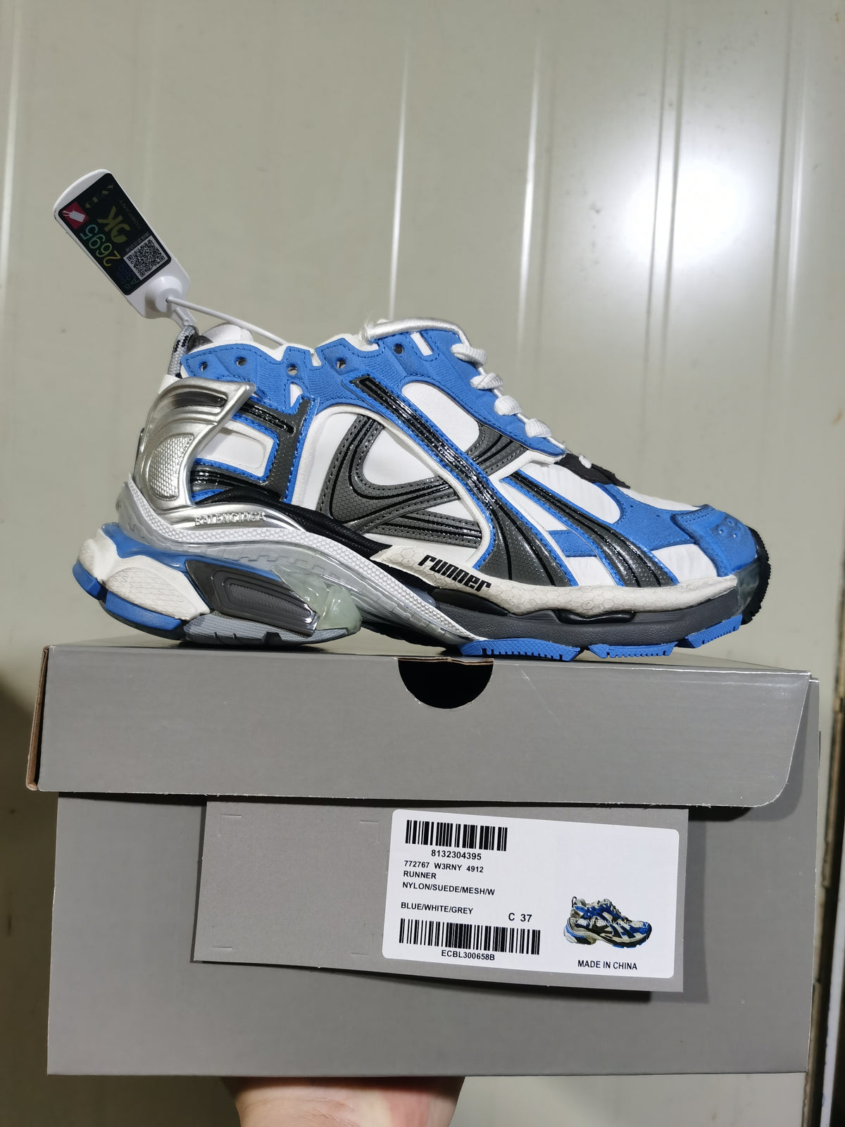 Puma Runner sneaker displayed on its box, with the label showing style 772677 W3NY, color BLUE/WHITE/GREY and photographed size C 37.