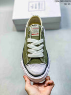 Top view of an olive sneaker showing the white laces, light toe cap, tongue label, and dark toe trim.