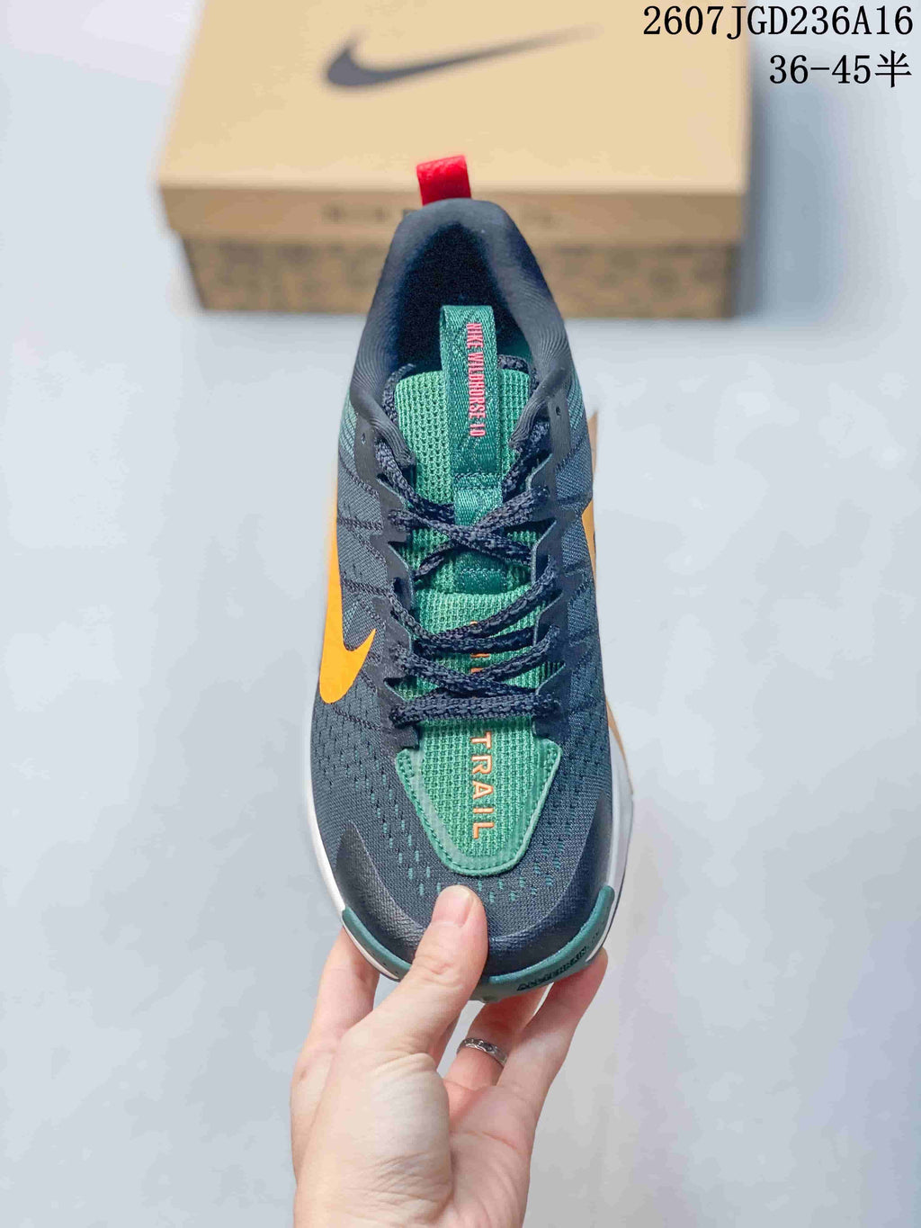 Top view of the sneaker showing dark laces, a green tongue, orange lettering, and contrasting orange side accents.
