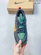 Top view of the sneaker showing dark laces, a green tongue, orange lettering, and contrasting orange side accents.