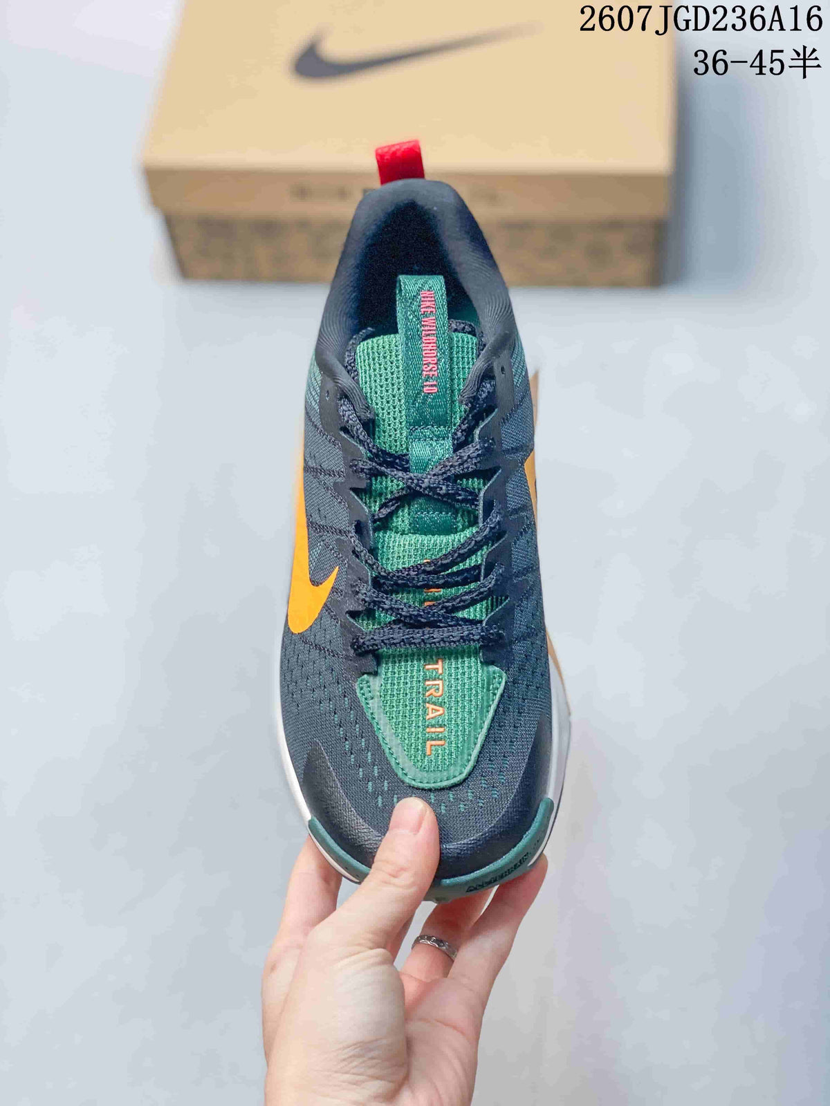 Top view of the sneaker showing dark laces, a green tongue, orange lettering, and contrasting orange side accents.
