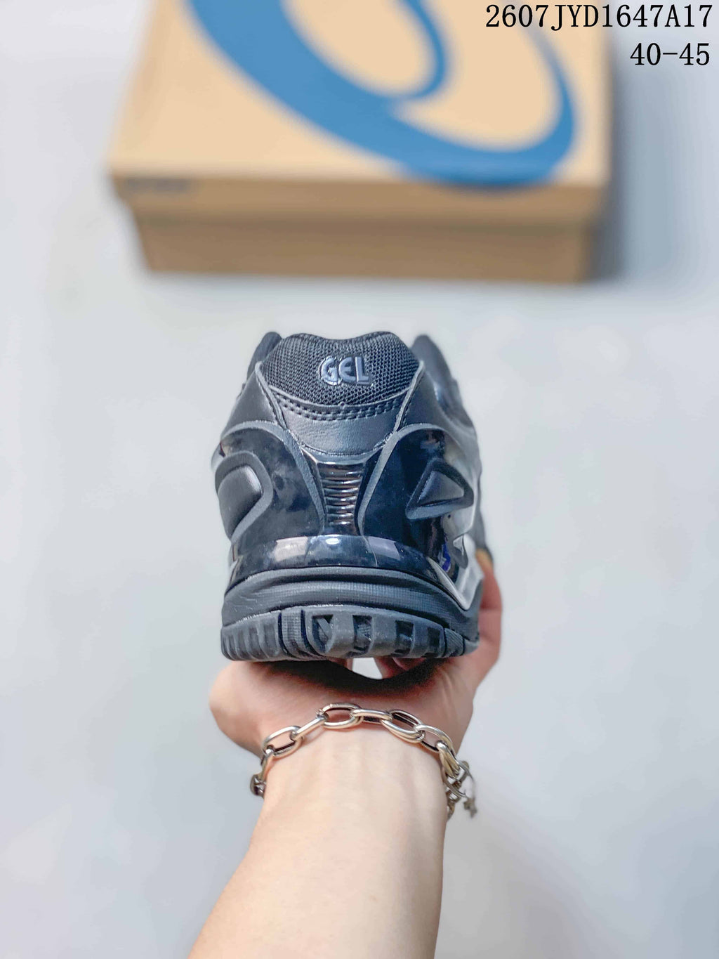 Rear view of a dark ASICS tennis shoe showing the padded heel and outsole tread; image text shows 2607JYD1647A17 and 40–45.