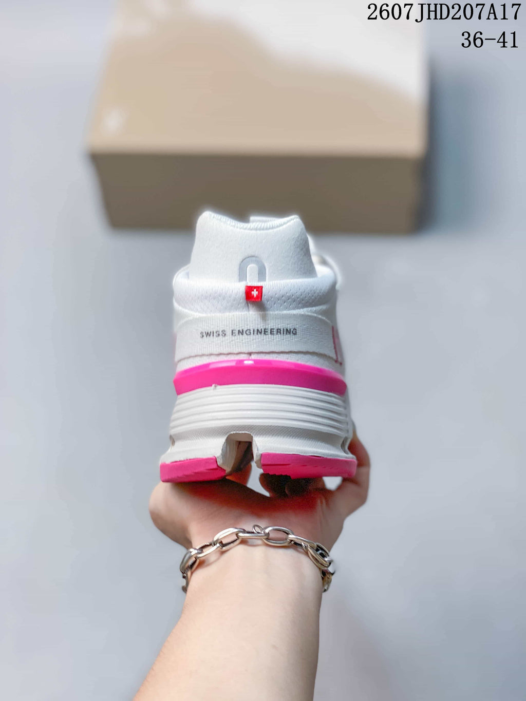 Rear view of the white sneaker showing the pink heel accent, On logo detail, and Swiss Engineering text.