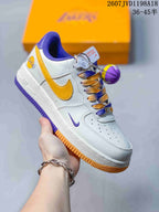 Angled side view showing the white low-top sneaker, gold Swoosh, purple detailing, and basketball accessory.