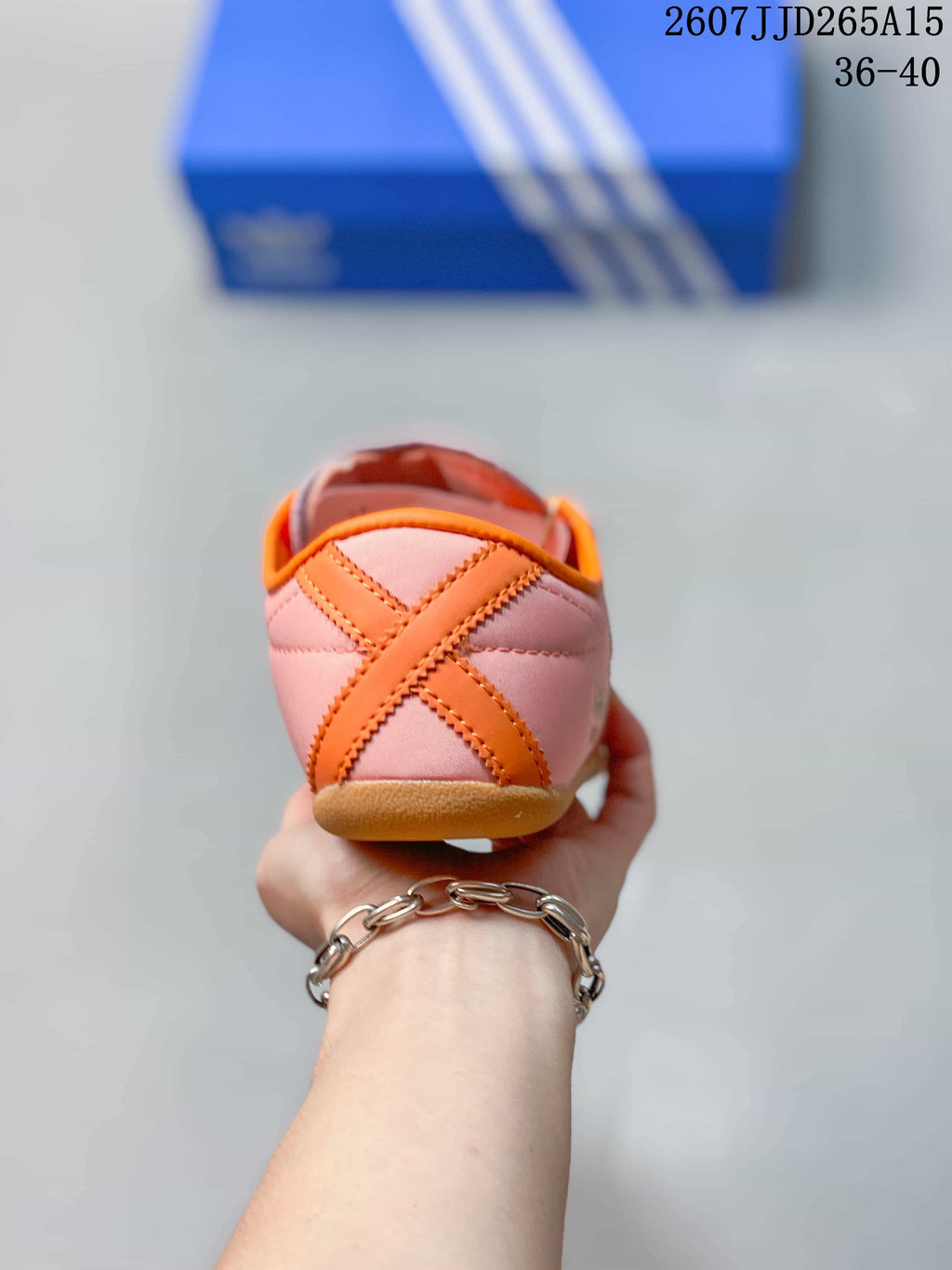 Rear view showing the pink heel, orange crossed detail, and gum-colored outsole.