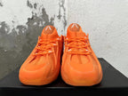 Front view of orange Adidas basketball sneakers with matching laces and high padded tongues.