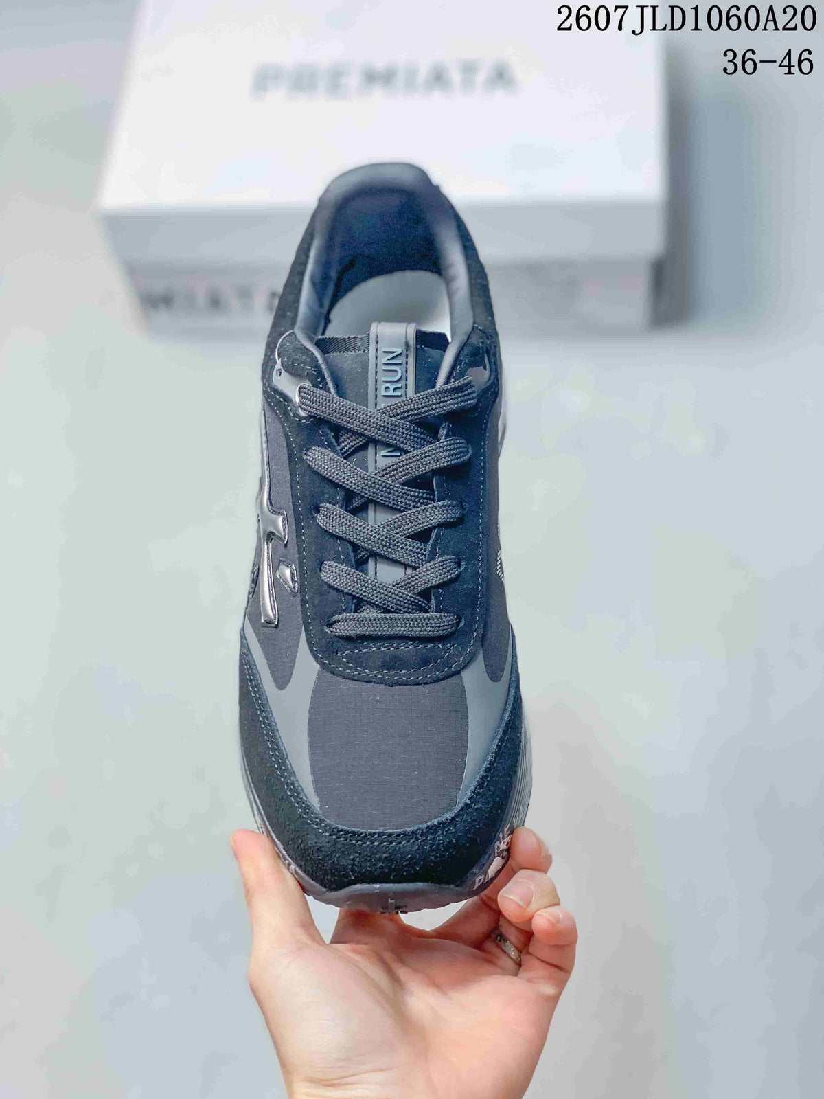 Top view of a black and gray lace-up trainer showing the tongue, eyelets, laces, and tonal panel construction.