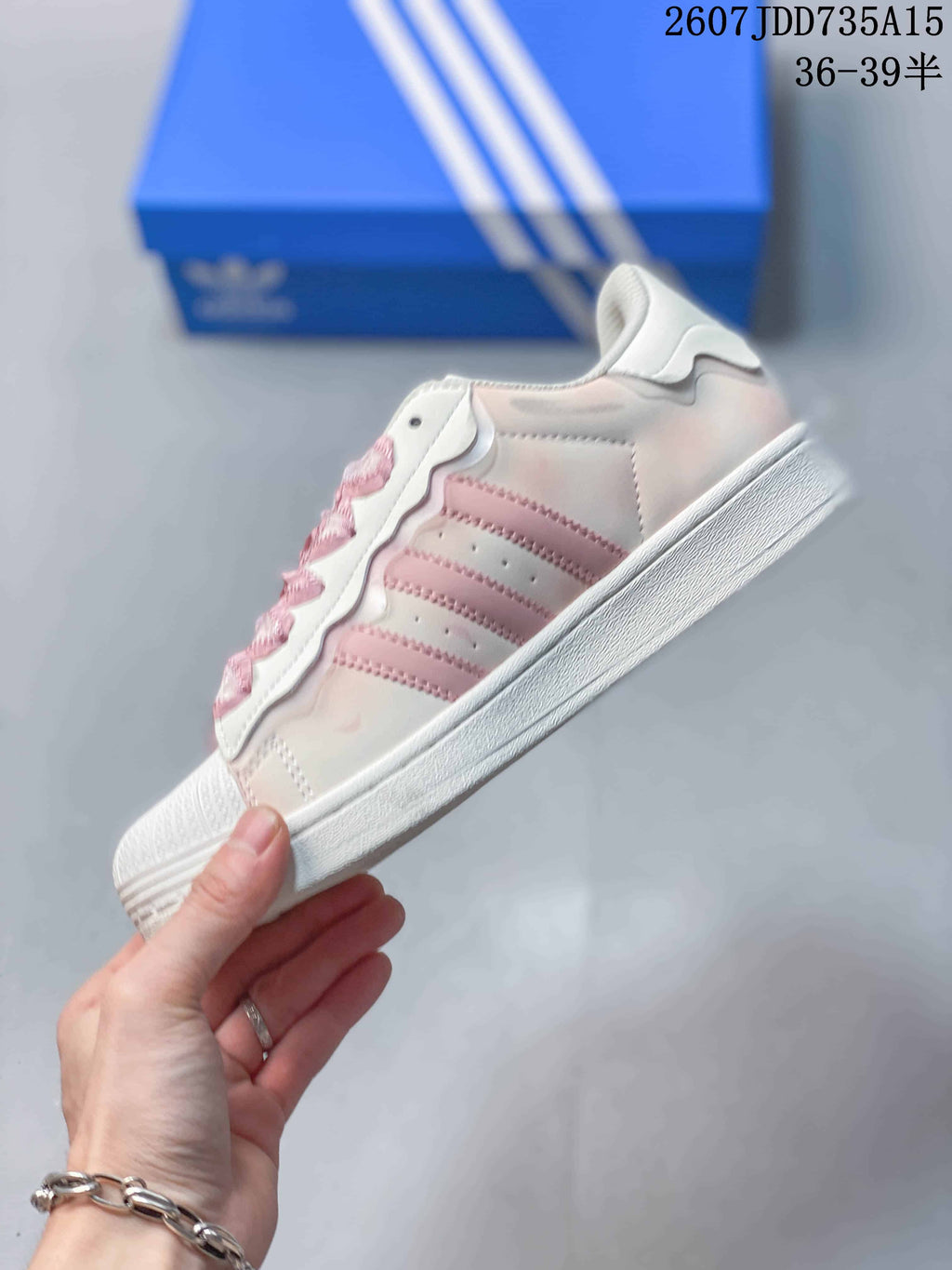 Side profile showing the pink three-stripe design, white upper panels, and low-profile sole.