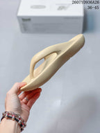 Side profile of the beige thong sandal showing its raised strap and molded sole shape.