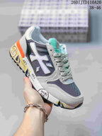 Angled side view of a grey and navy Premiata sneaker with mint-green tongue accents, orange heel detail and a black outsole; image text shows 2607 TYD110A20 and 38–46.