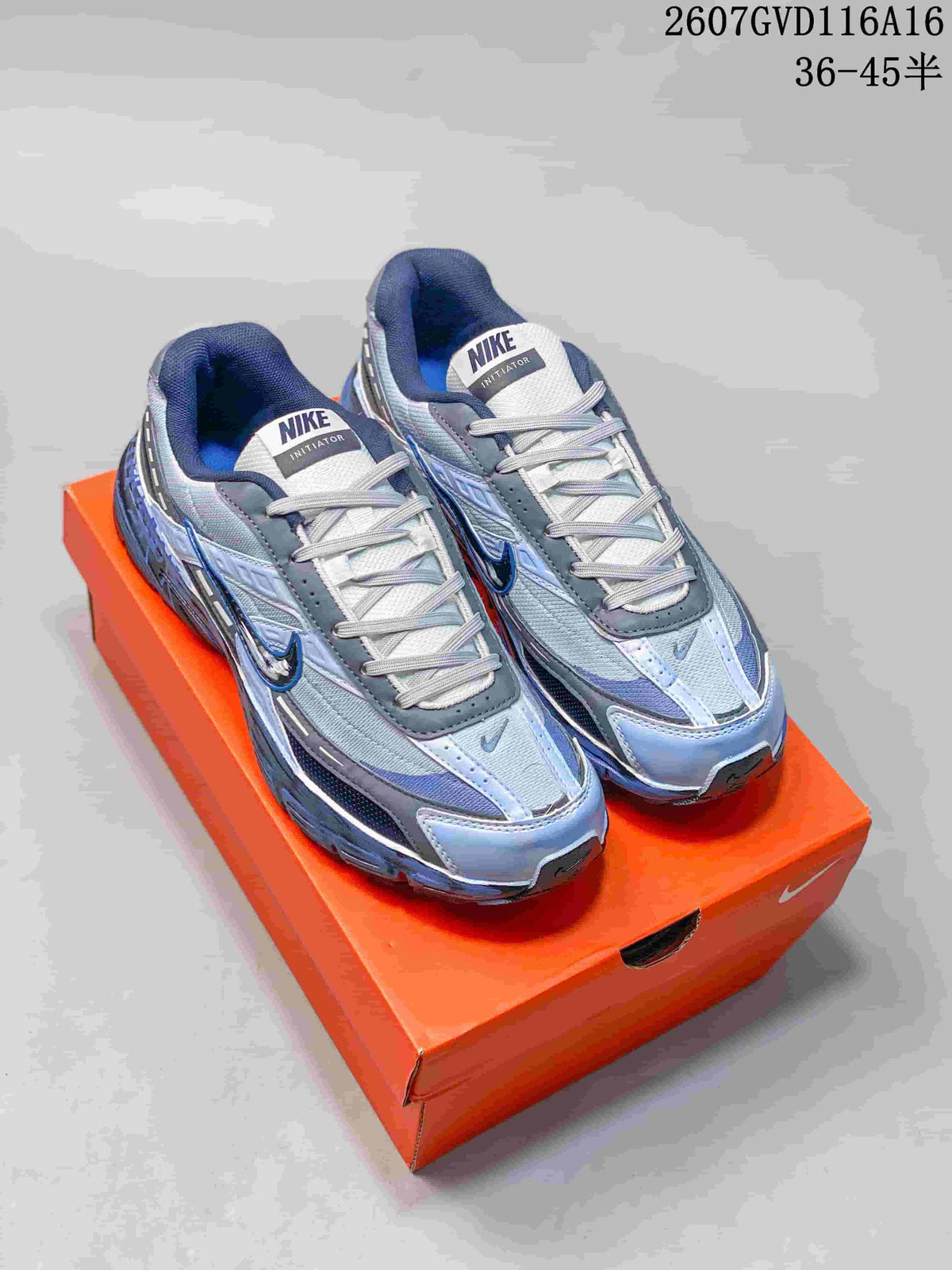 Pair of blue and gray Nike Initiator sneakers displayed on an orange shoebox.