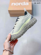 Side view highlighting the light gray upper, off-white accents, thick speckled midsole, and lugged outsole.