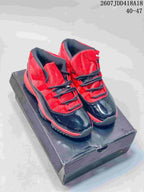 Black and red high-top sneakers with glossy black toe panels and red upper sections displayed on a dark shoebox.
