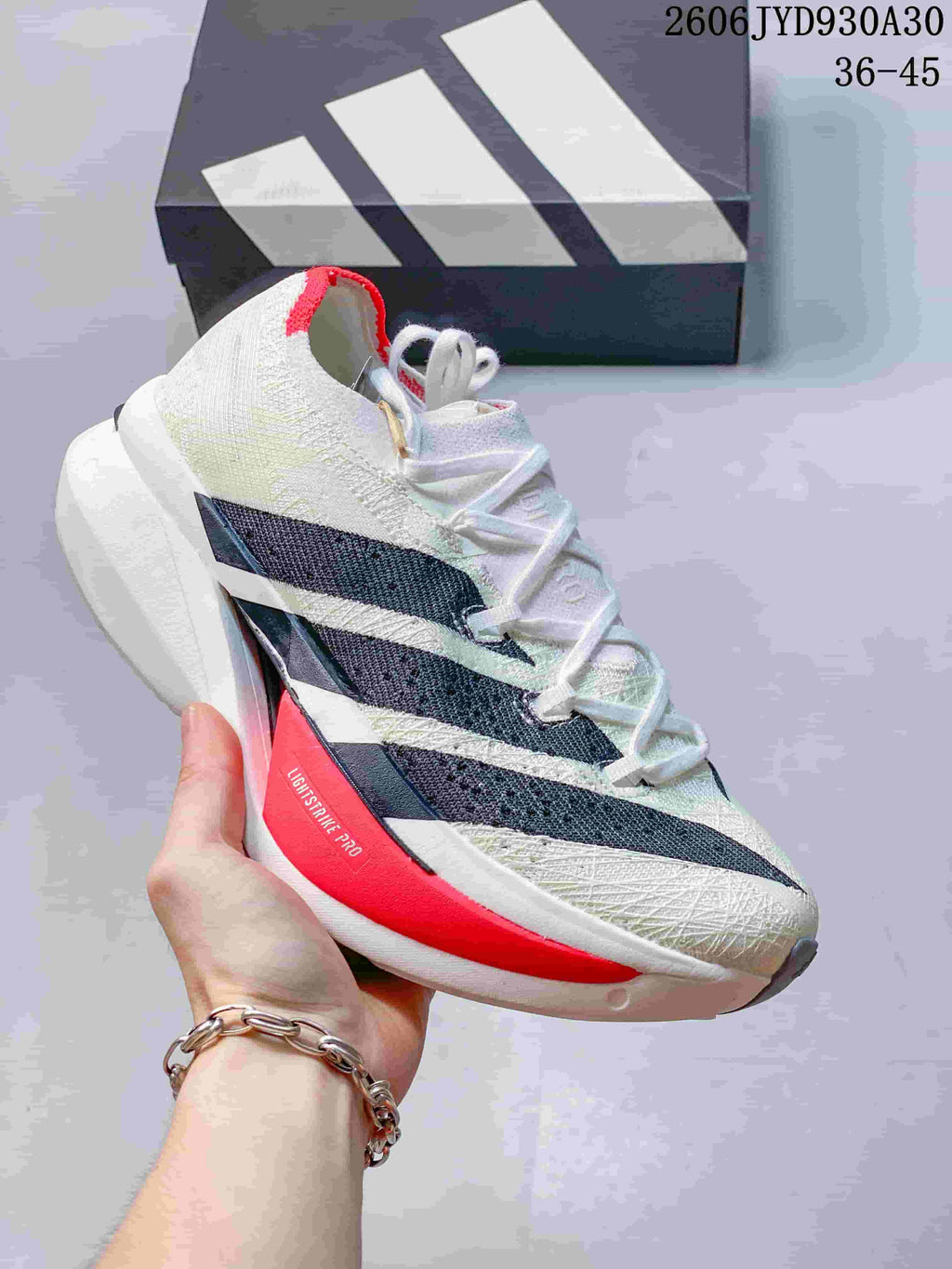 White adidas Adizero Prime X3 shoe with dark stripes and a pink sole accent.