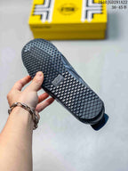 Bottom view of a black sneaker showing the patterned rubber outsole and tread.