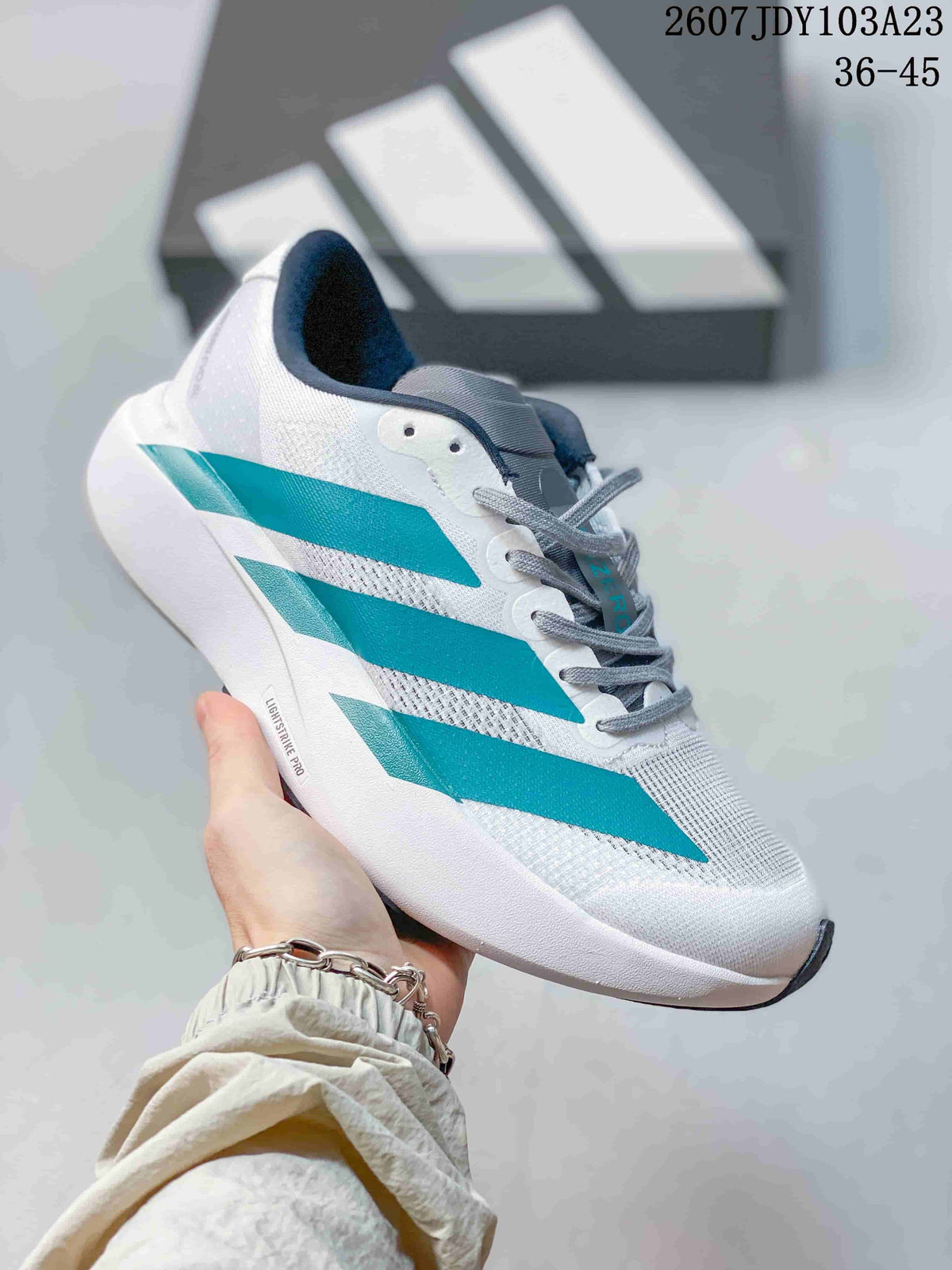 White adidas Adizero low-top sneaker with turquoise side stripes and a white sole.