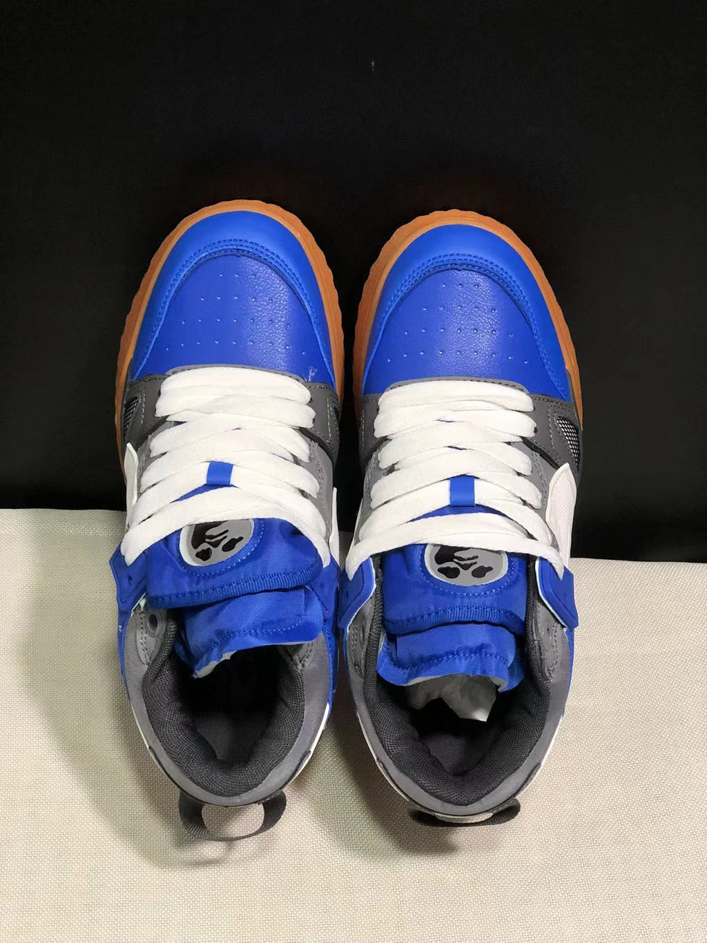 Top view of blue, white, and grey sneakers showing the padded tongues, white laces, and contrasting toe panels.