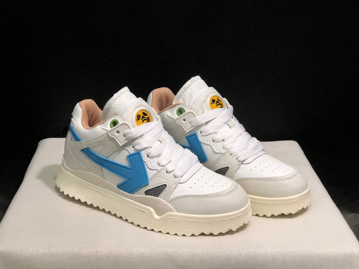 Front three-quarter view of the pair highlighting the white upper, blue side arrows, and cream-colored soles.