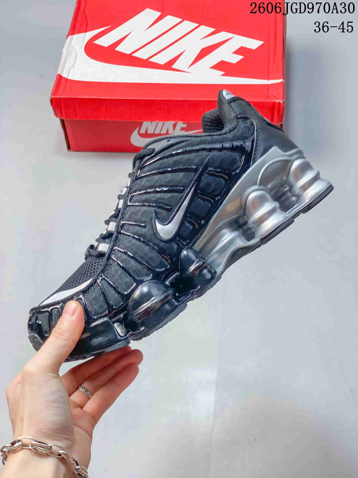 Side view of a dark Nike Shox TL sneaker with silver accents and sculpted sole units