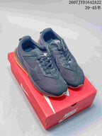 Pair of black Nike low-top sneakers displayed on a red shoebox, with gum-colored outsoles and visible heel air units.