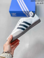 Side profile showing the low-top shape, black side stripes, grey toe panel and brown outsole.