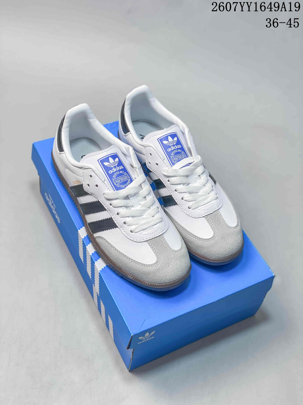 Pair of white adidas Samba sneakers with black stripes displayed on a blue adidas shoebox; image text shows style code 2607YY1649A19 and size range 36–45.