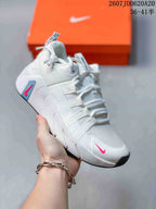 White Nike training sneaker with blue and pink accents, layered side straps and a contrasting black outsole.
