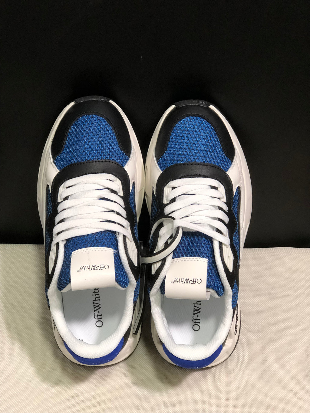 Top view showing blue textured panels, black overlays, white laces, and branded tongue labels.