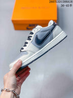 Side profile showing the white and light gray upper, dark navy side logo, white midsole, and dark outsole accents.