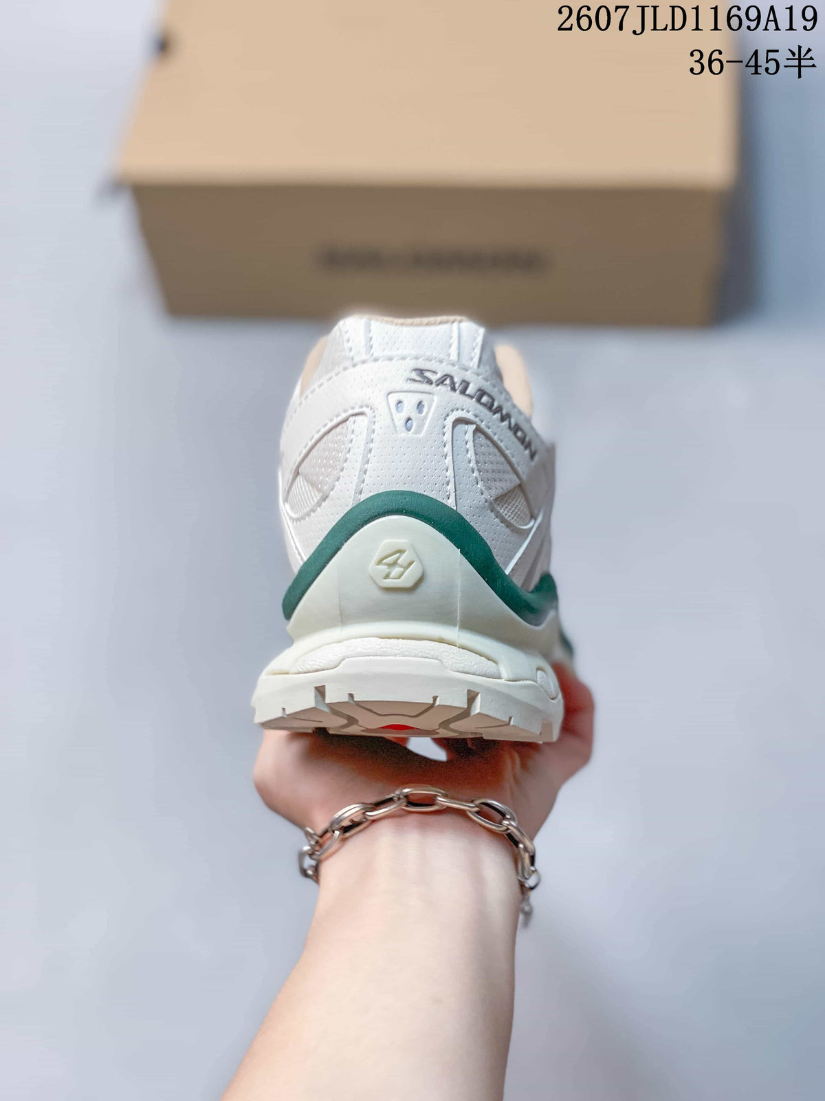 Rear view of a white Salomon XT-Quest sneaker showing the heel structure, green accent trim and outsole tread.