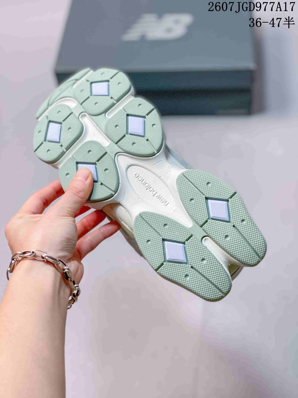 Underside view of a New Balance 9060 sneaker showing the segmented outsole with mint green tread sections.