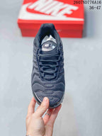 Top view of a black Nike Air Max Plus sneaker showing the textured toe box, layered panels, tongue, and lace system.