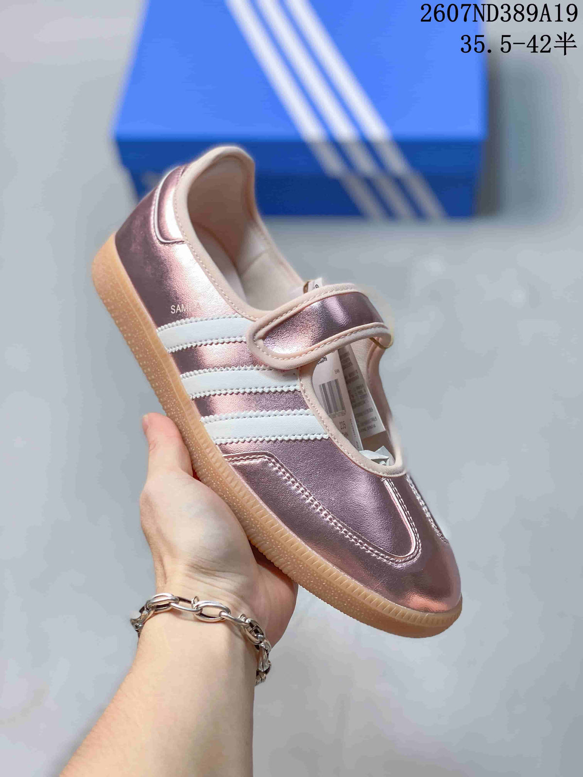 Side view of a pink metallic Samba Jane sneaker showing the strap, three stripes, and gum-colored outsole.