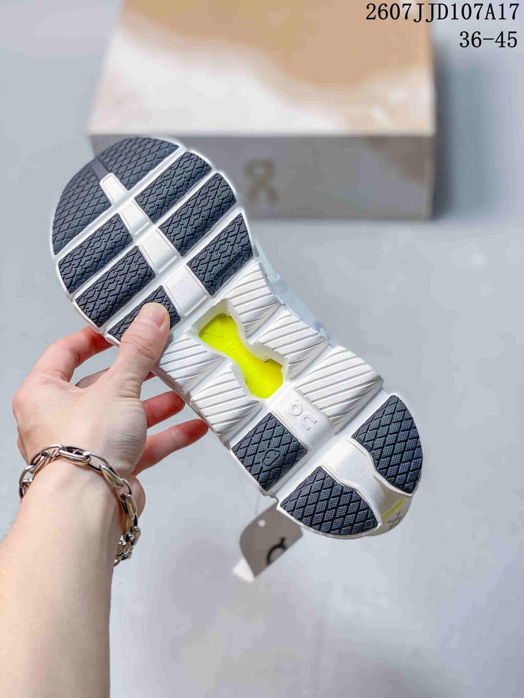 Bottom view of the sneaker showing a segmented white outsole, dark traction sections, and a central lime-colored opening.