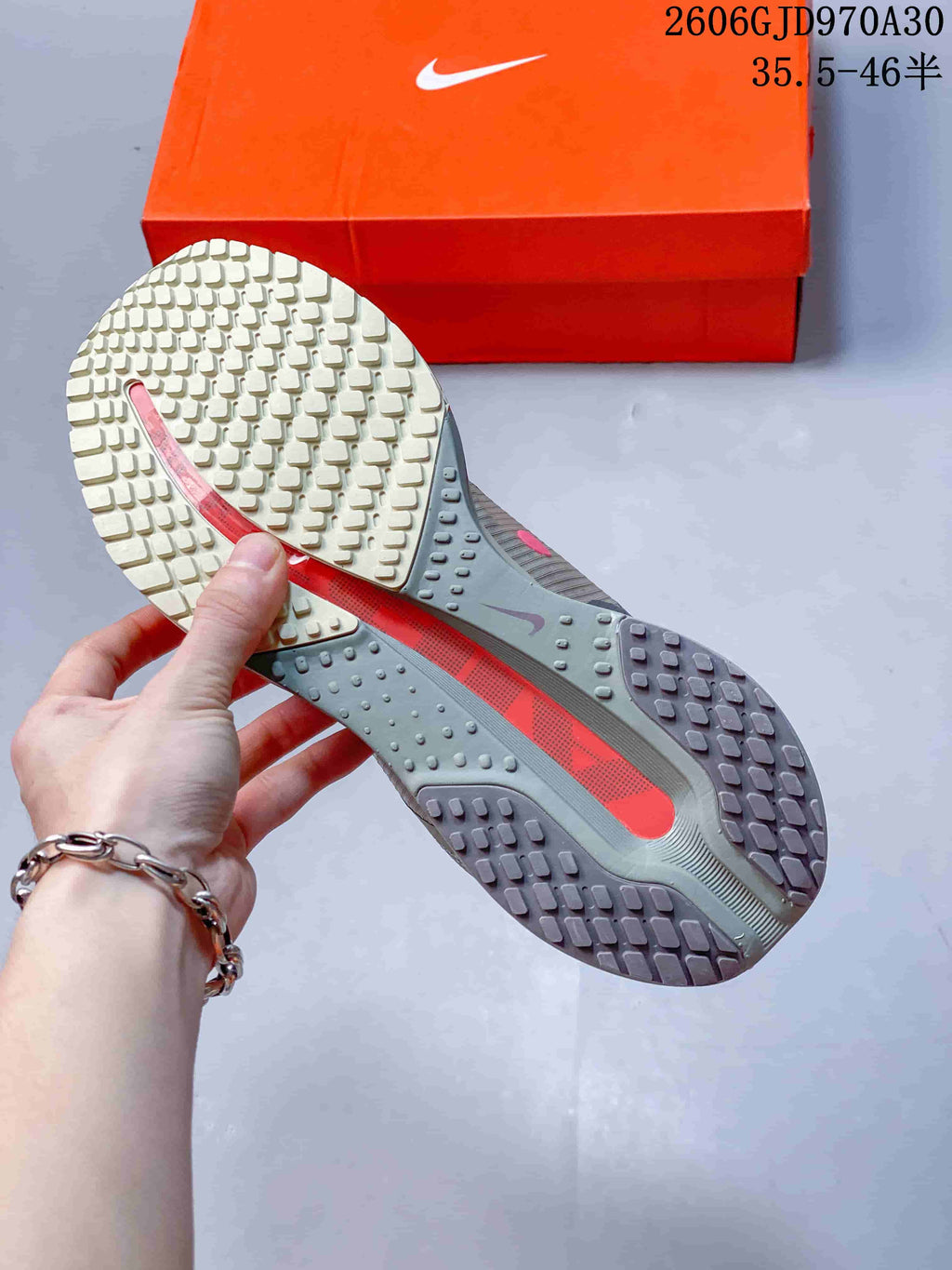 Close view of the patterned outsole with orange central detail and an orange Nike shoe box.