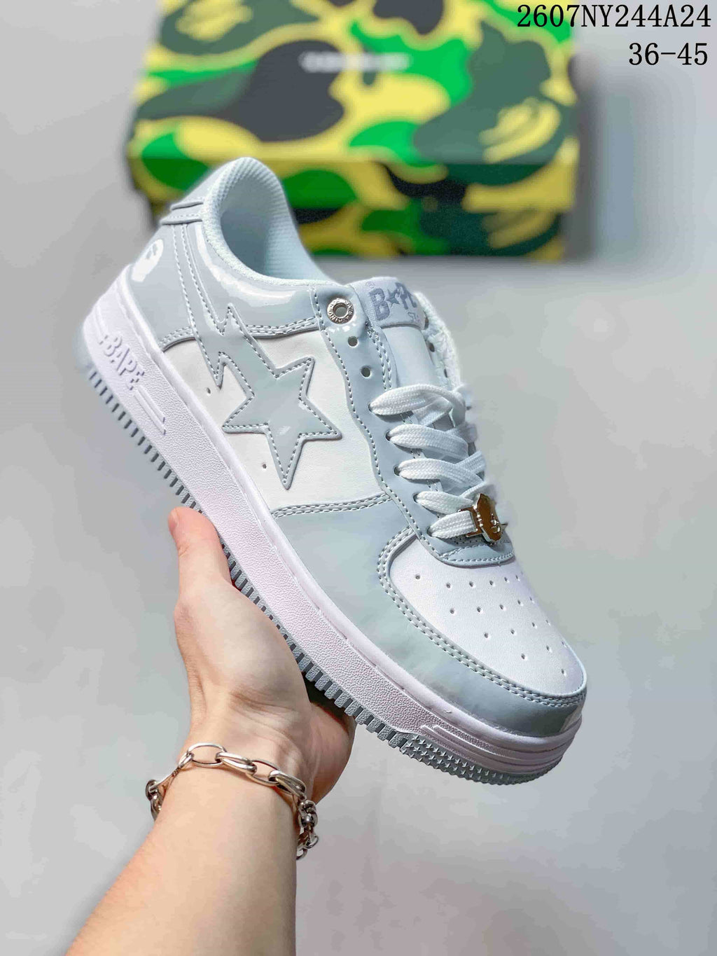 White low-top sneaker with pale gray star side graphic, white laces and white sole; source overlay shows style code 2607NY244A24 and size range 36–45.