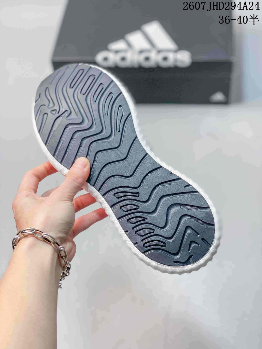 Close-up of the patterned outsole on a black, pink and white adidas sneaker.