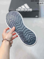 Close-up of the patterned outsole on a black, pink and white adidas sneaker.